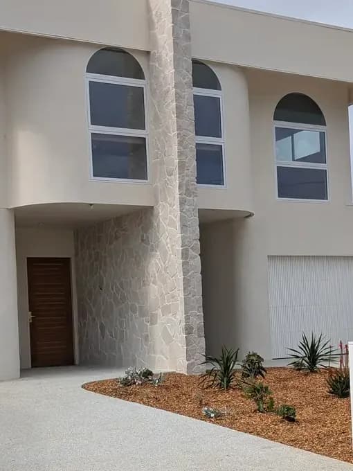 The curved stair bays and stone wall between the two homes of the finished Long Jetty Duplex