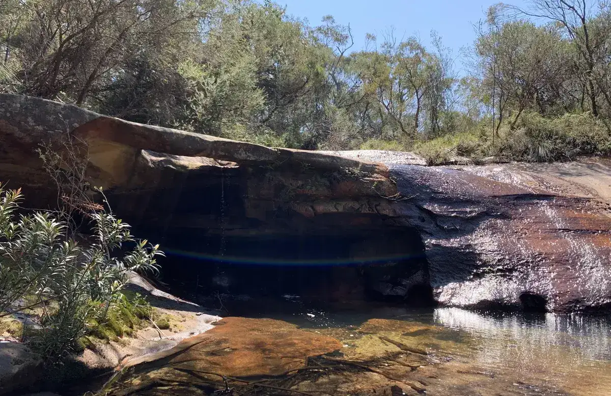 Sandstone overhang above a still rock pool near Little Wobby's waterfall