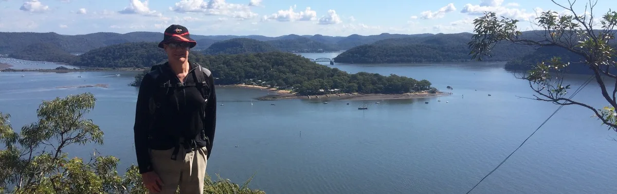 Hiker overlooking a river bend near Wondabyne with a bridge in the distance