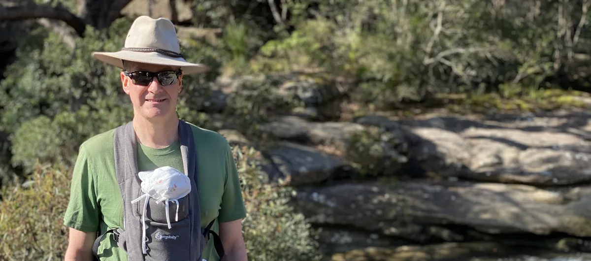 Hiker wearing a wide brim hat and sunglasses beside Piles Creek at Girrakool