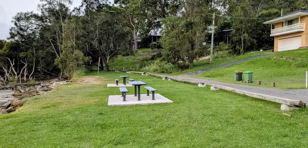 Picnic tables and mown foreshore reserve near houses at Hardys Bay