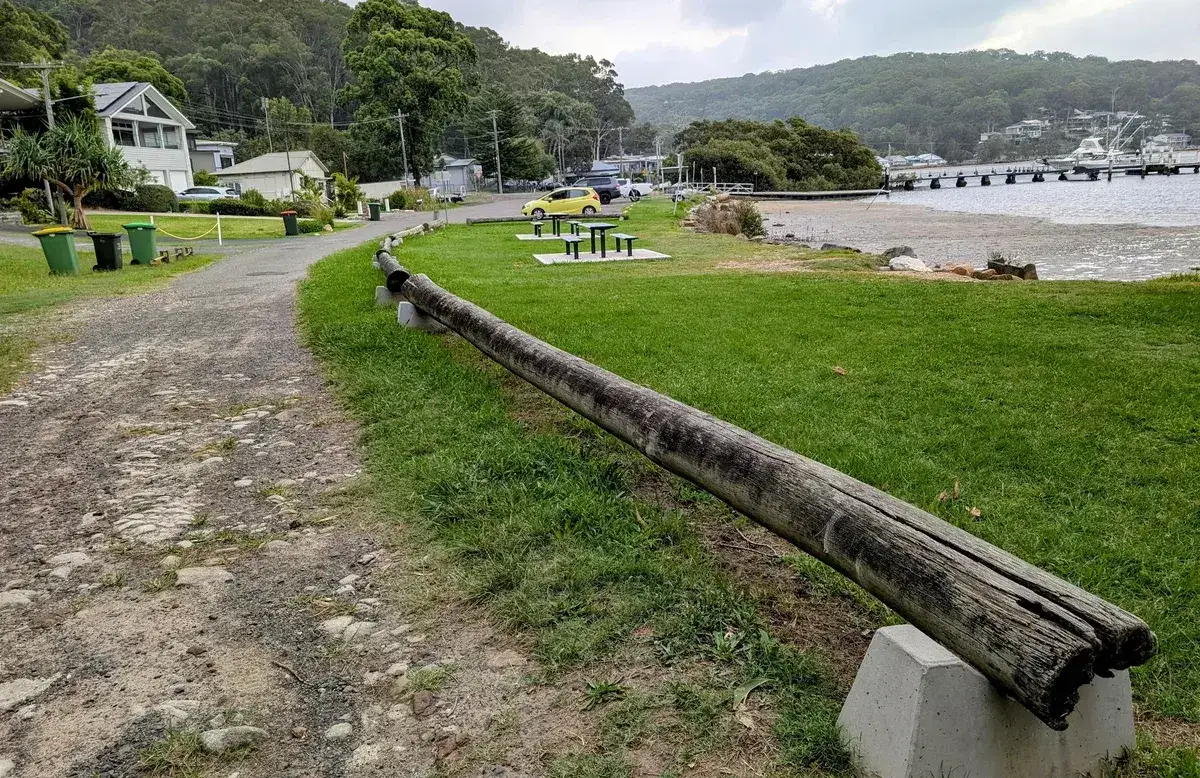 Log guard rail beside picnic tables and beach along Hardys Bay foreshore