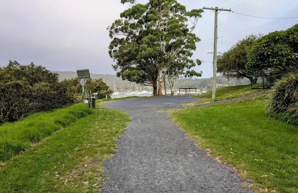Wide gravel path leading to a waterside picnic shelter at Hardys Bay