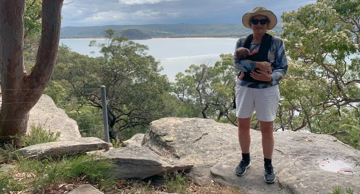 Woman with a baby carrier at a sandstone lookout above Lobster Beach