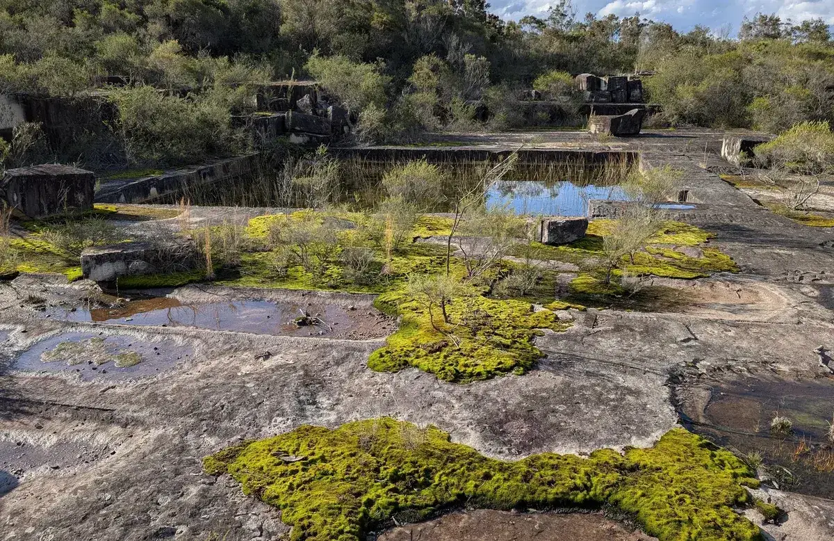 Aerial view of moss covered quarry ruins with pooled rainwater