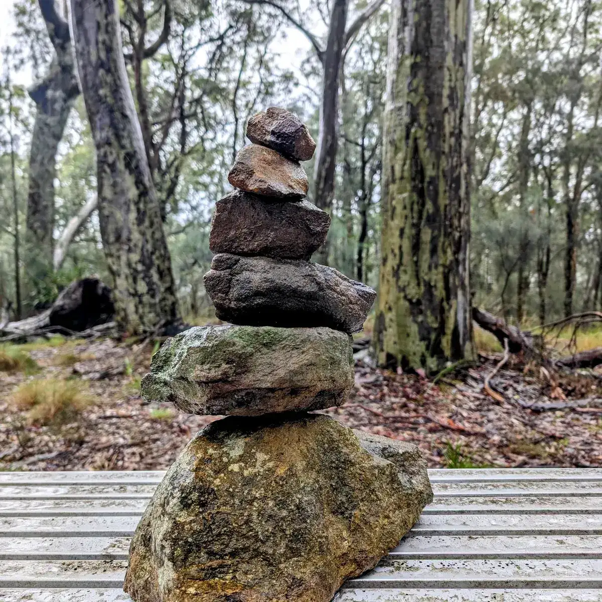 Small stone cairn balanced on a park bench rail