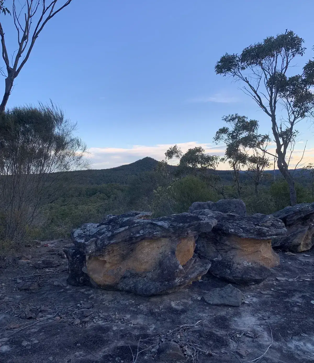 Sandstone boulders frame a dusk view of Mount Wondabyne's peak