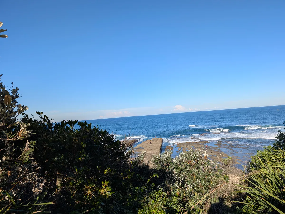 Ocean view from the Norah Head coastal walk over the heath to the rock platform, beach and breaking waves, a good spot for whale watching in winter