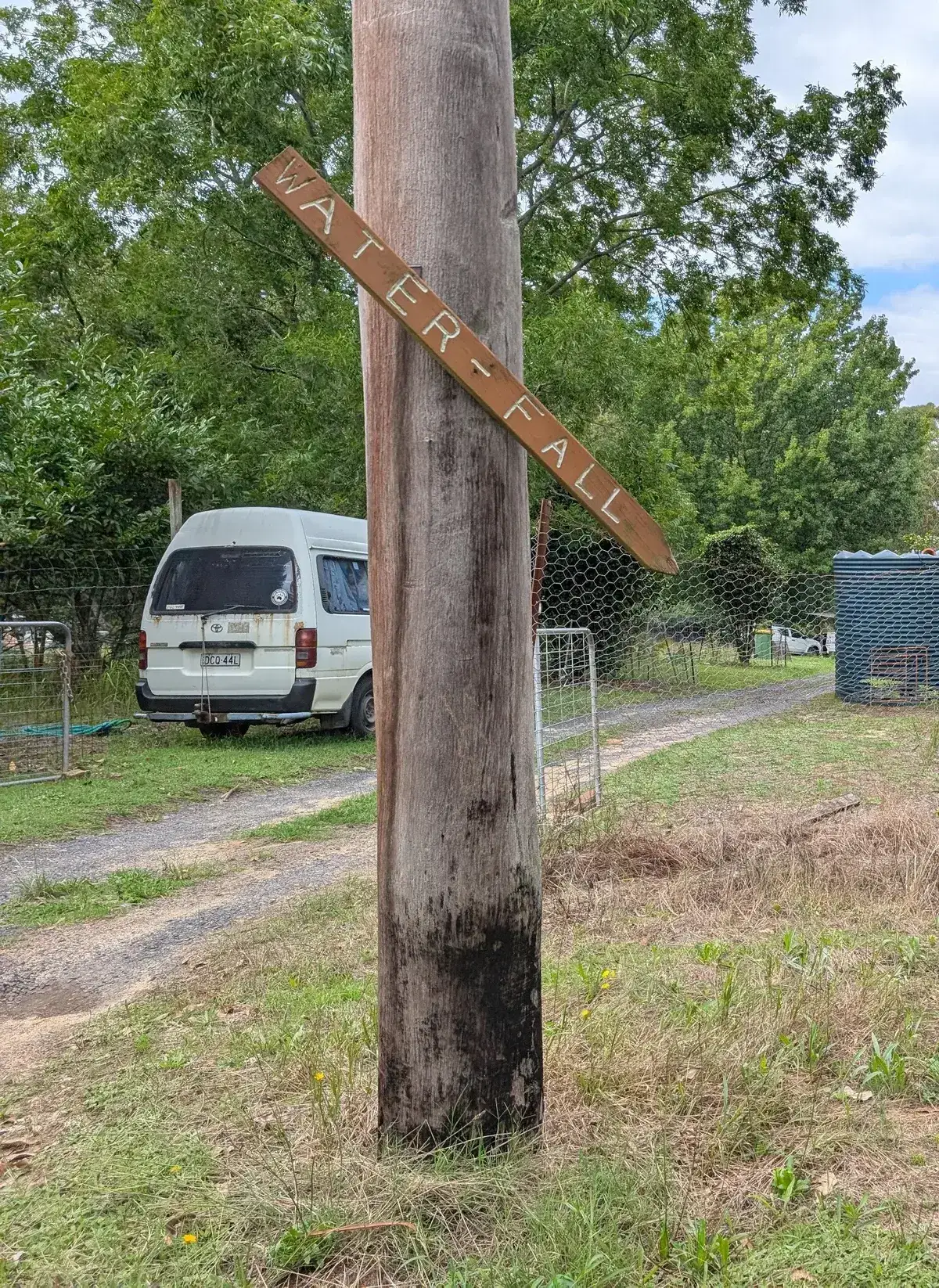 hand painted waterfall sign nailed to a power pole beside a parked van