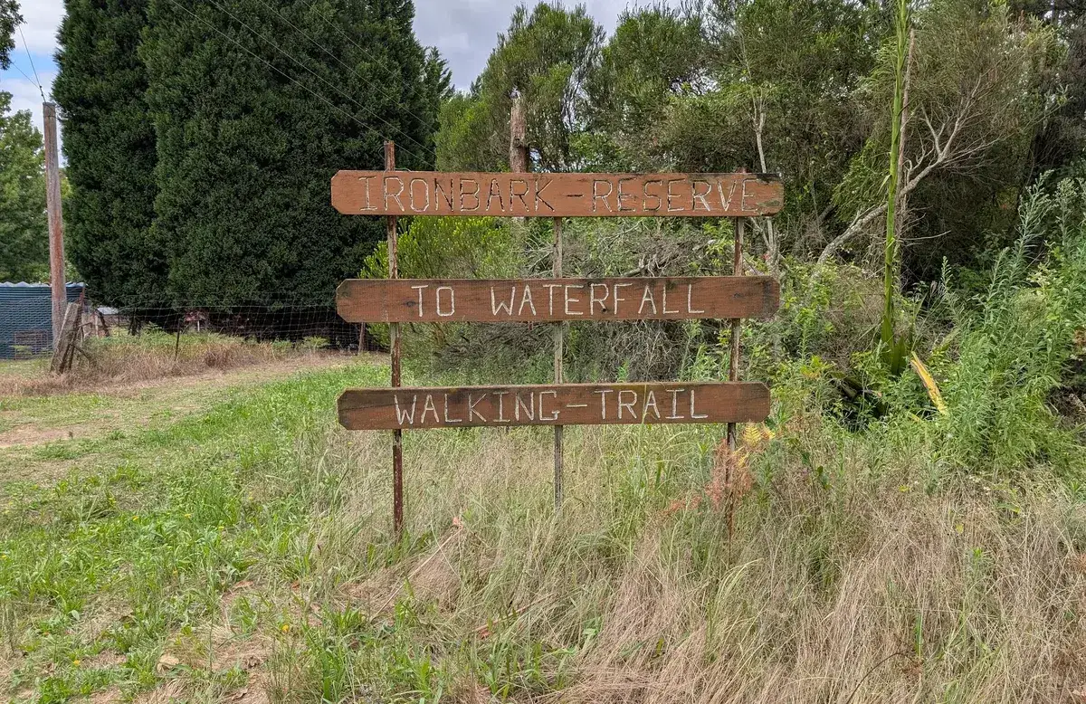 weathered timber sign reading Ironbark Reserve to waterfall walking trail