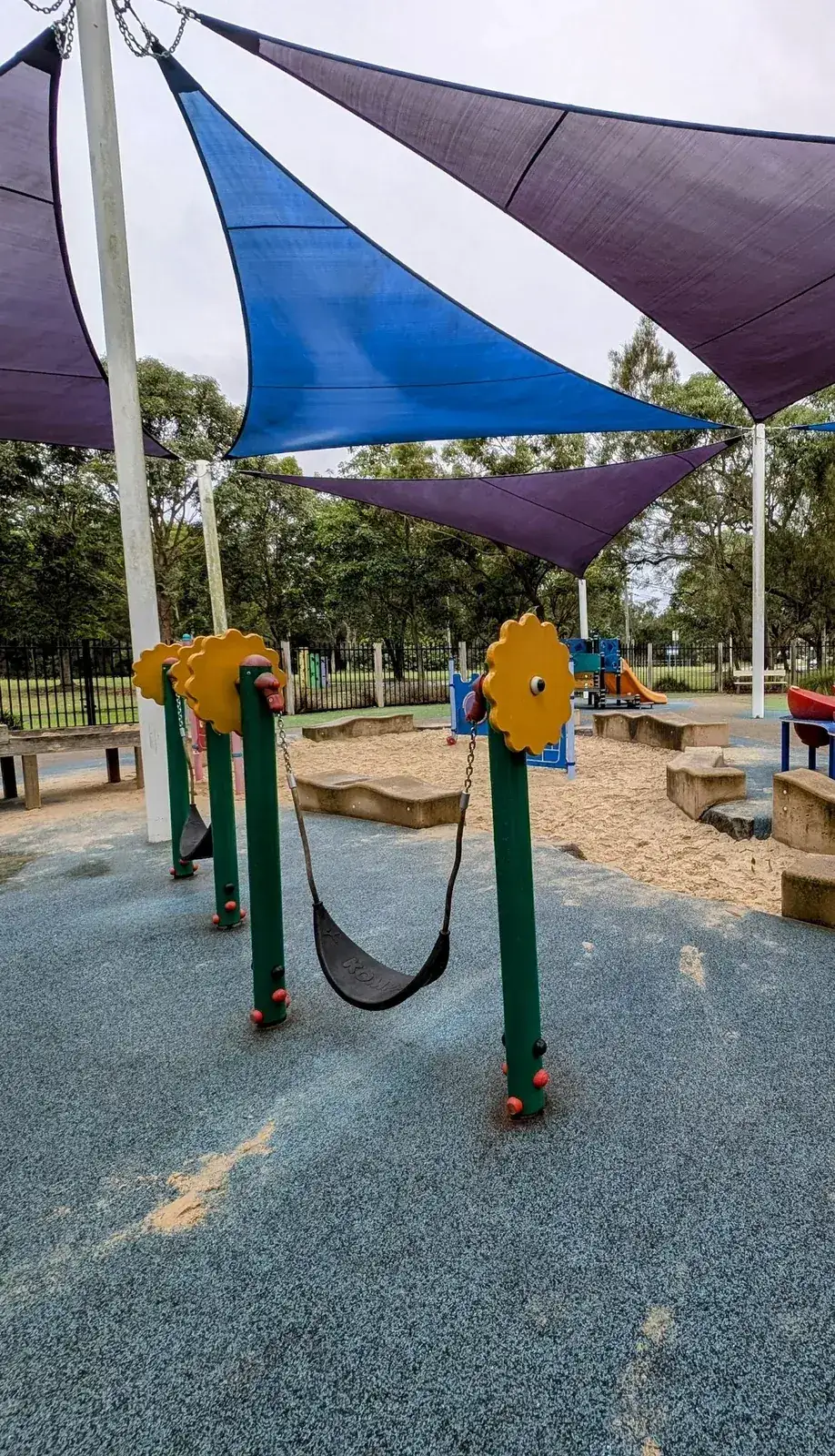 school playground with shade sails, a sandpit and flower shaped swing posts
