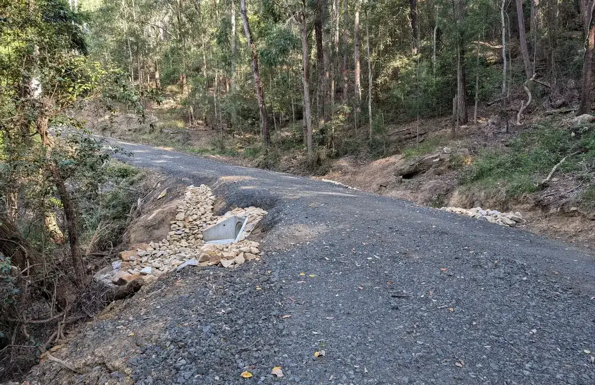 gravel fire trail with a stone lined culvert repair crossing a drainage dip