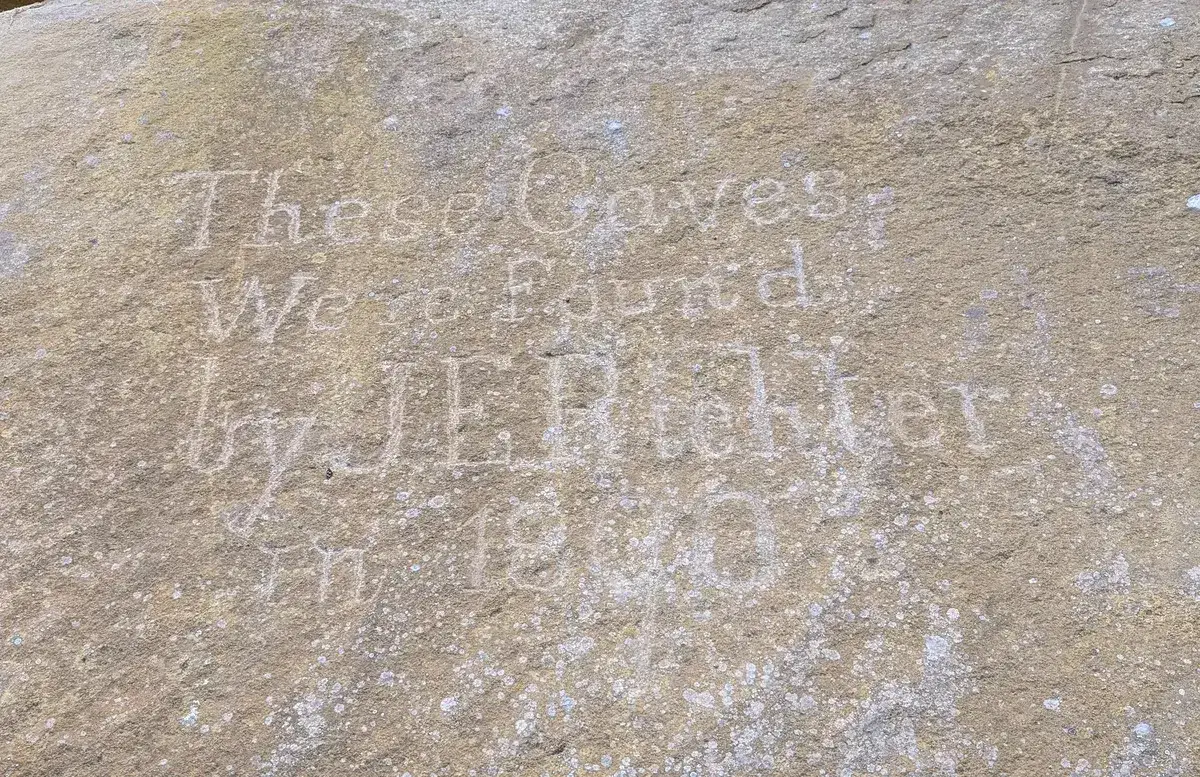 sandstone boulder engraved with 'these caves were found by J E Richter' and a date
