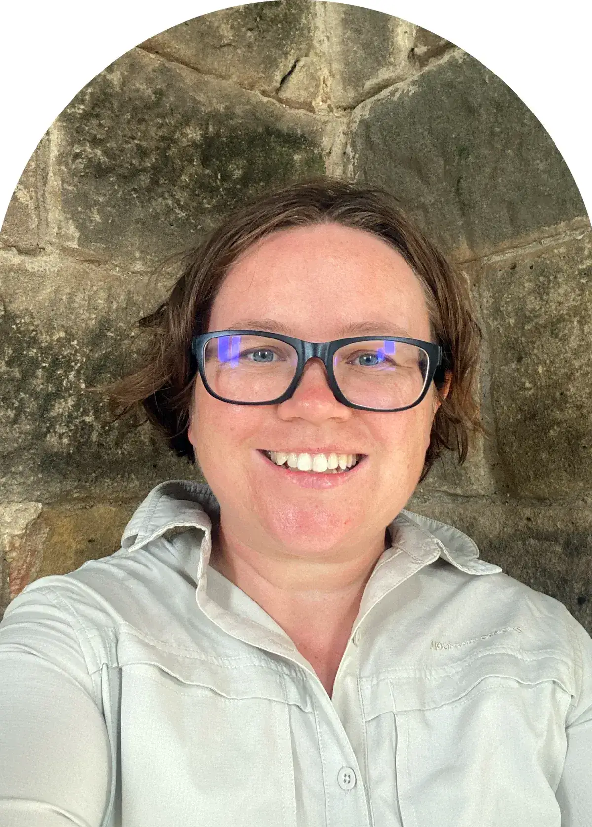 Portrait of Shea Cullen smiling in front of a sandstone wall