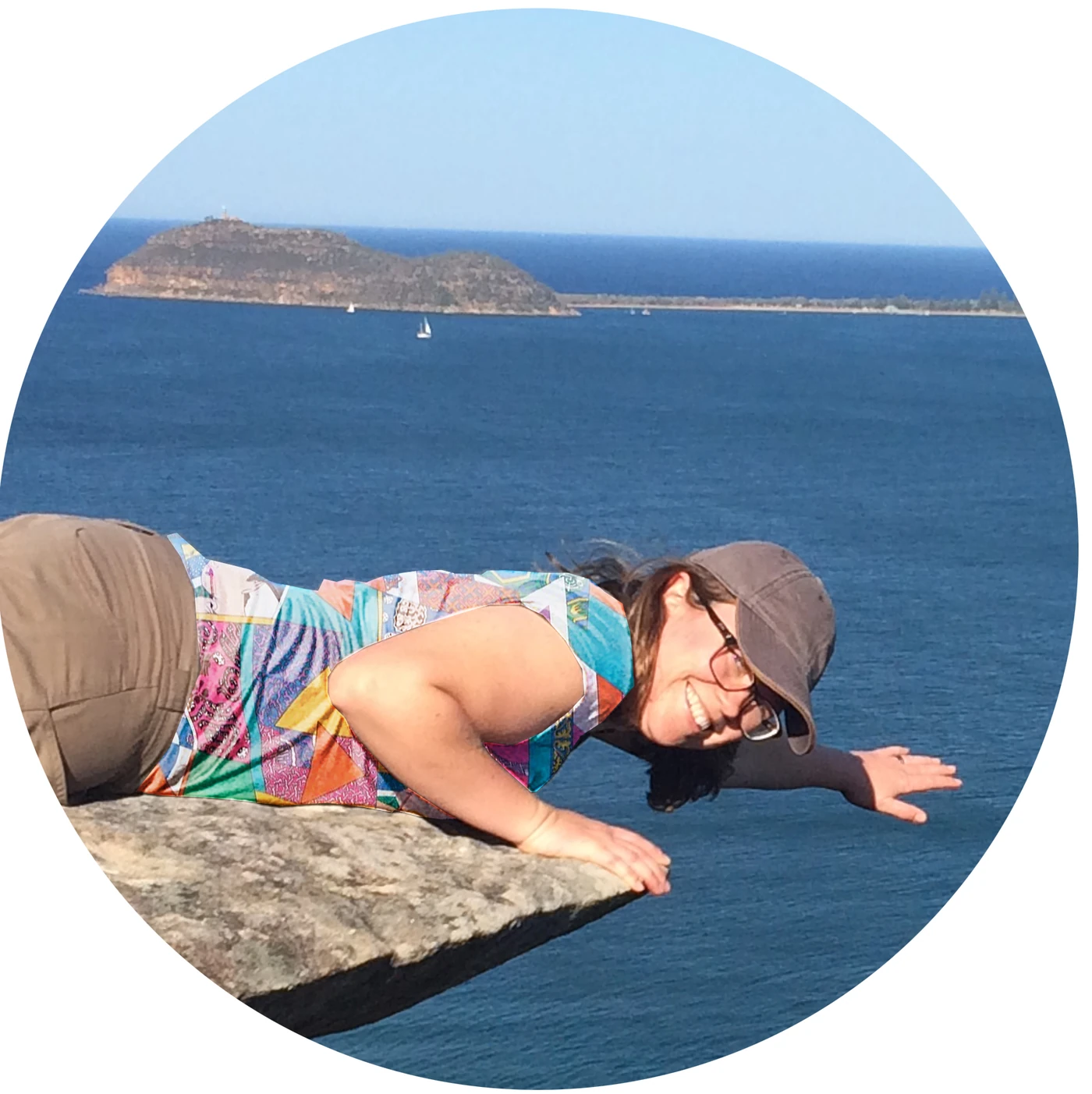 Woman posing on a cliff edge overlooking the water and island