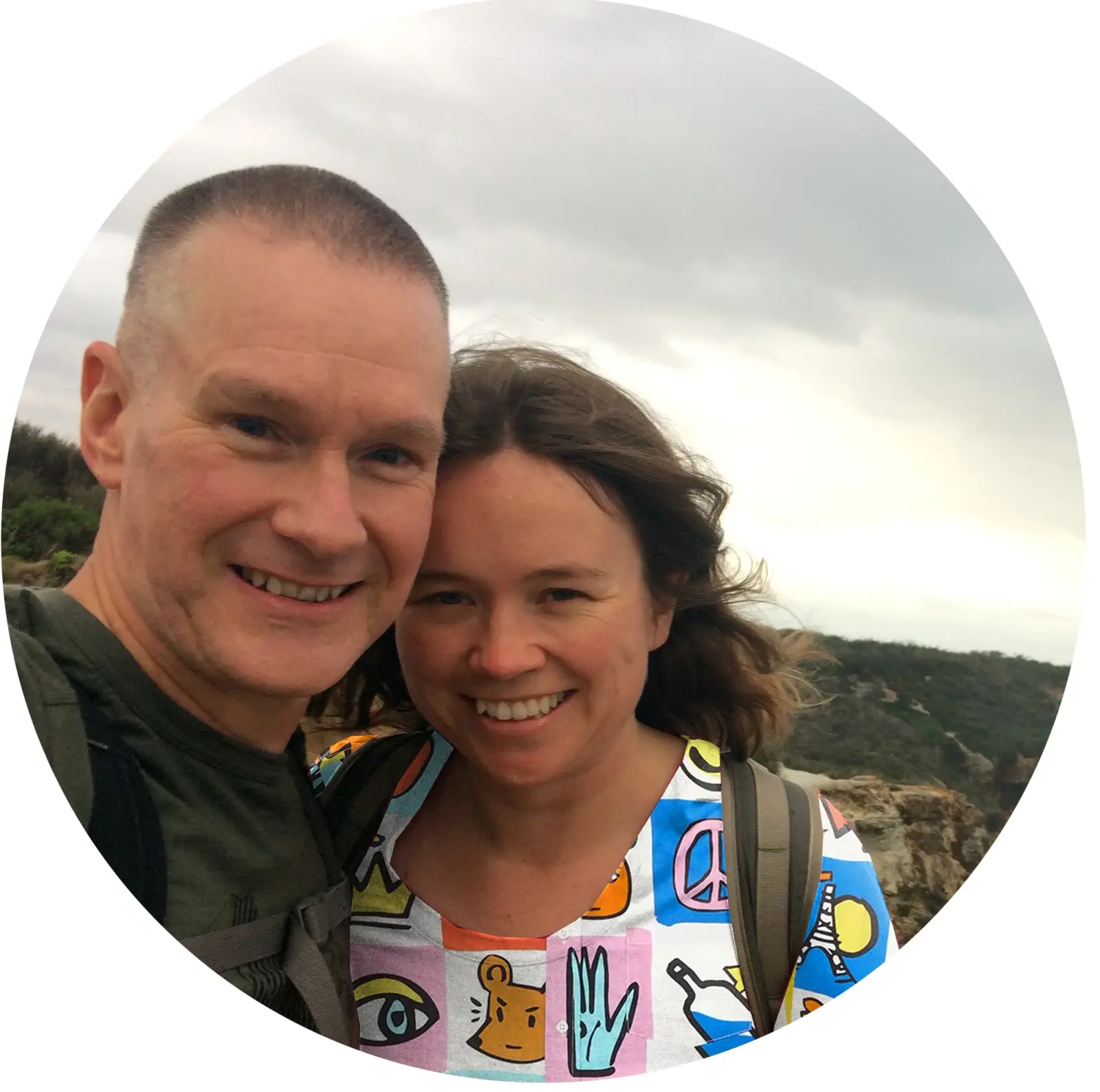 Shea and Dave smiling together on a cliff top bushwalk