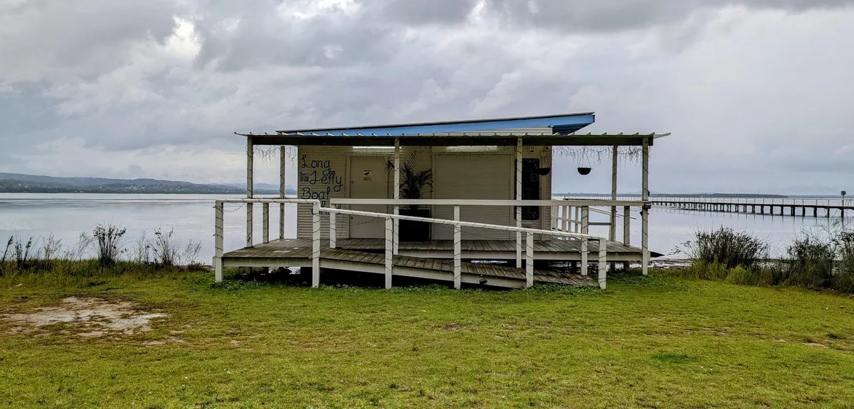 Long Jetty boatshed with a blue awning on the lake shore