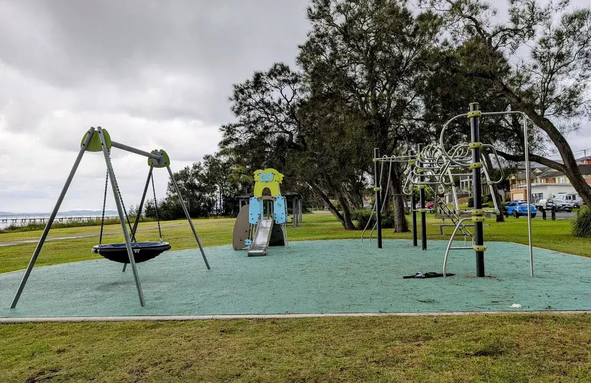 children's playground with swings and climbing equipment by the lake